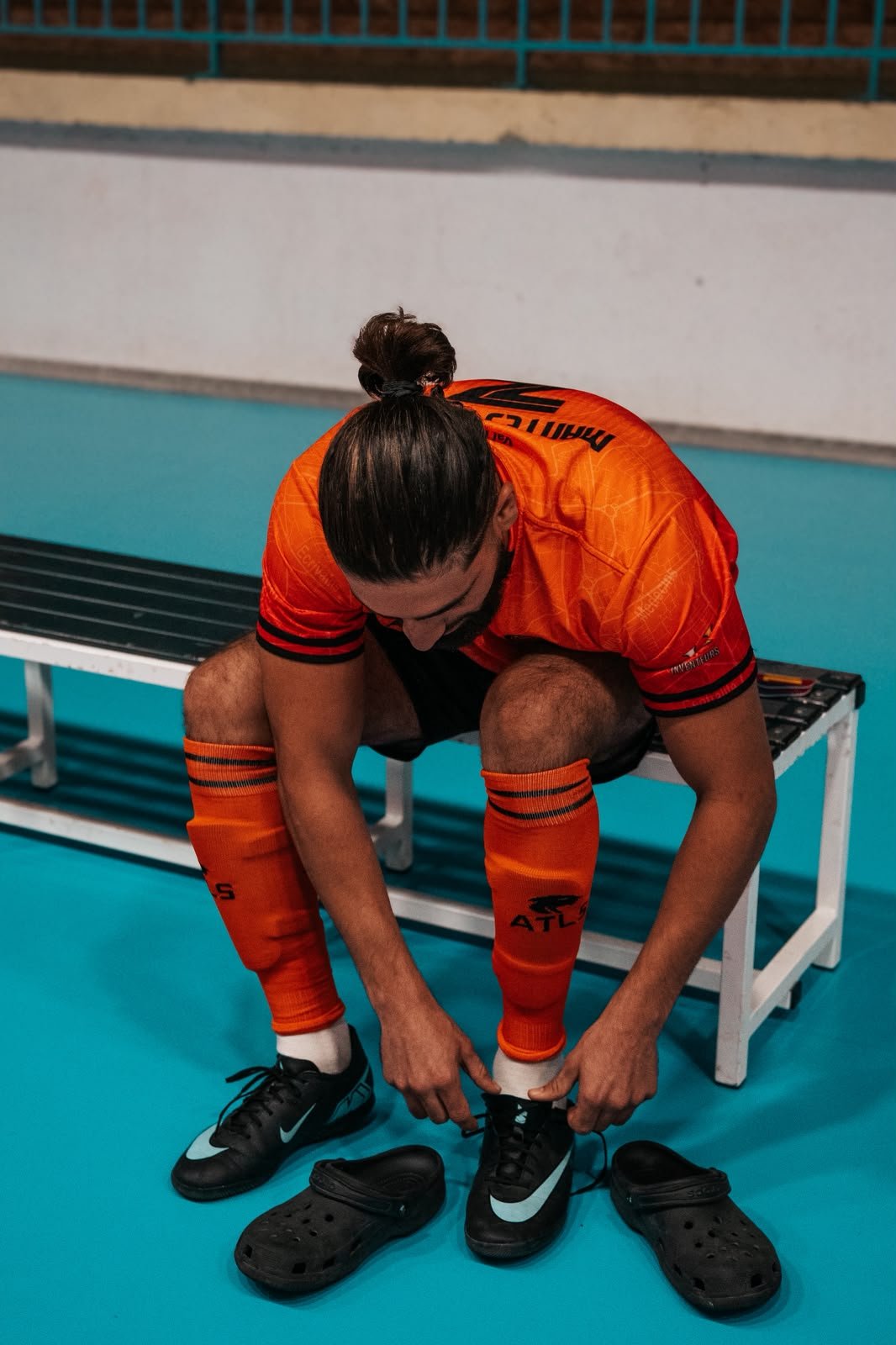 Joueur de Mantes Futsal qui lace ses chaussures, chaussettes orange Atls